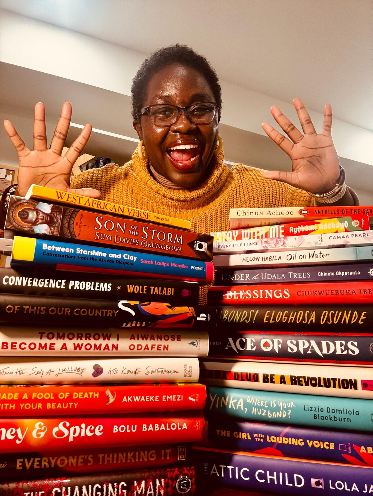 an image of Kammy, a dark-skinned Black nonbinary femme person with type 4B hair cut short at the camera with their hands extended and a wide smile on her face. Kammy has on minimal brown eye makeup and burgundy lipgloss. she is wearing a yellow sweater /